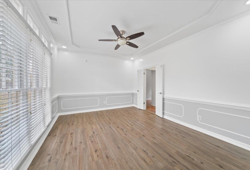 Spare room with a decorative wall, a wainscoted wall, wood finished floors, recessed lighting, and a raised ceiling