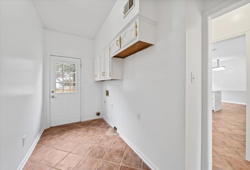 Washroom with cabinet space, washer hookup, and light tile patterned flooring