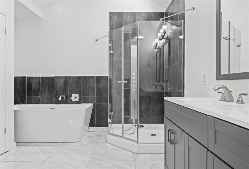 Full bathroom featuring a freestanding tub, vanity, a shower stall, and light marble finish flooring