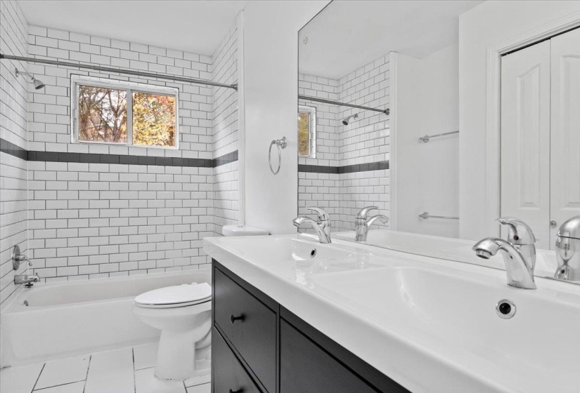 Full bath featuring  shower combination, double vanity, and light tile patterned floors