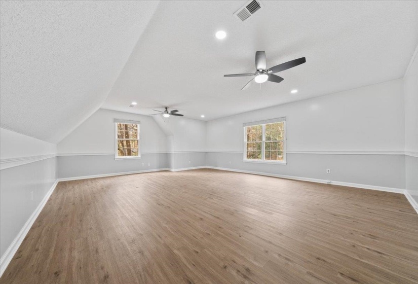 Additional living space featuring light wood-style floors, a textured ceiling, ceiling fan, recessed lighting, and lofted ceiling