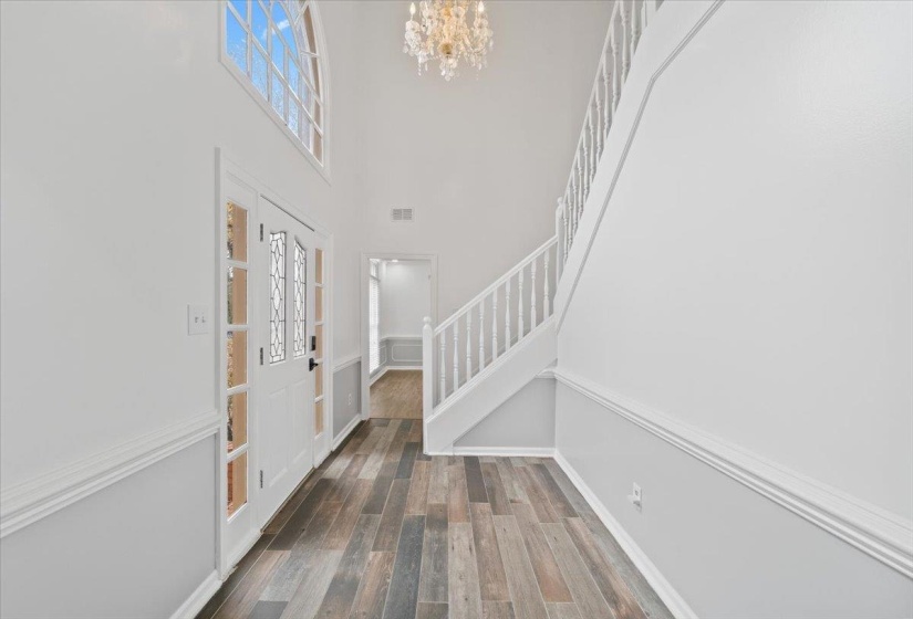 Entryway with stairway, a chandelier, dark wood-style flooring, and a towering ceiling