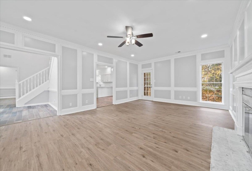 Unfurnished living room featuring built in shelves, light wood-style floors, ceiling fan, a fireplace, and a decorative wall