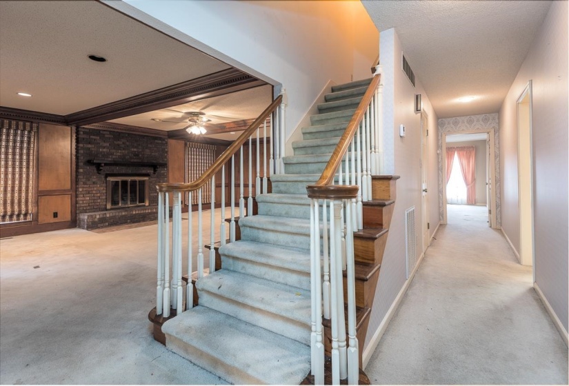 Staircase featuring a textured ceiling, a brick fireplace, and carpet