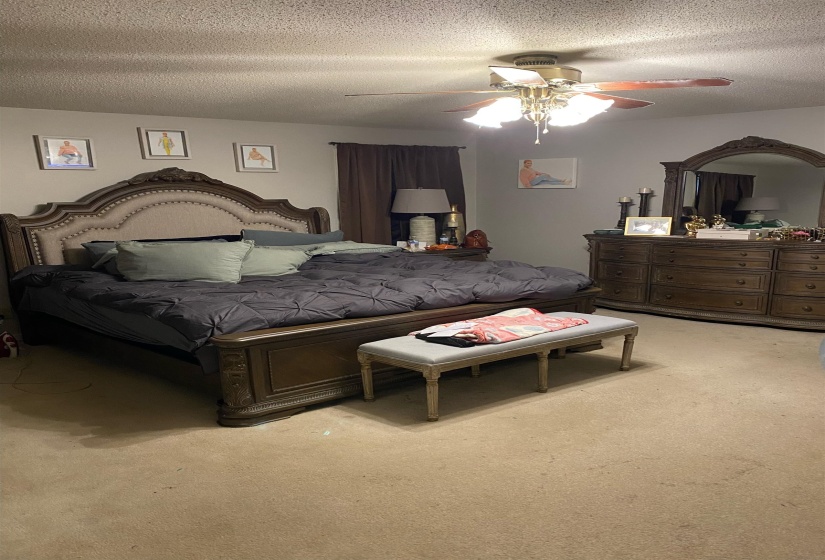 Bedroom with a ceiling fan, a textured ceiling, and light colored carpet