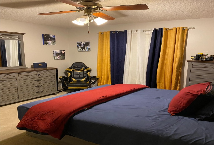 Carpeted bedroom featuring a textured ceiling and a ceiling fan