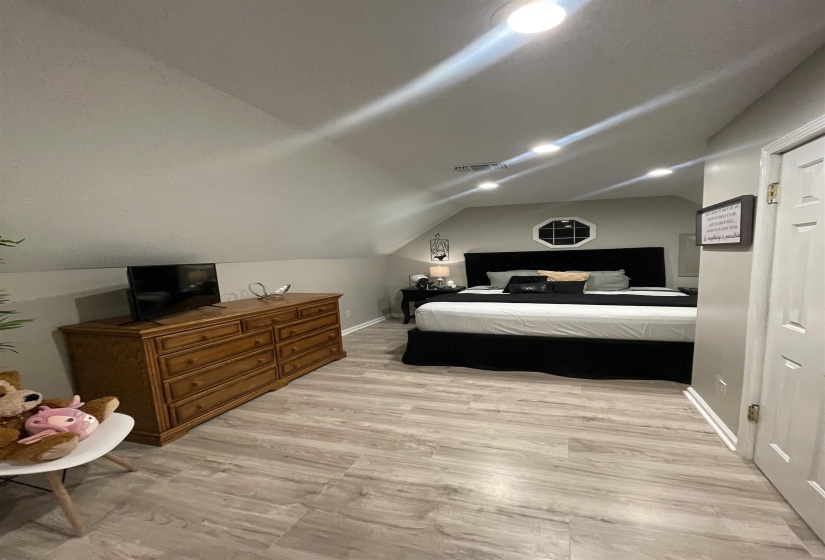 Bedroom with light wood-type flooring and lofted ceiling