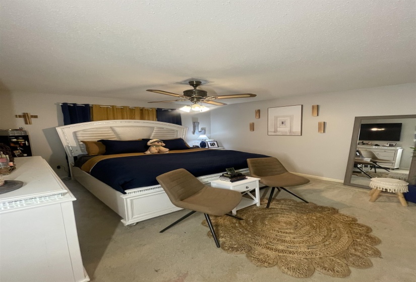 Bedroom featuring a textured ceiling, a ceiling fan, and carpet floors