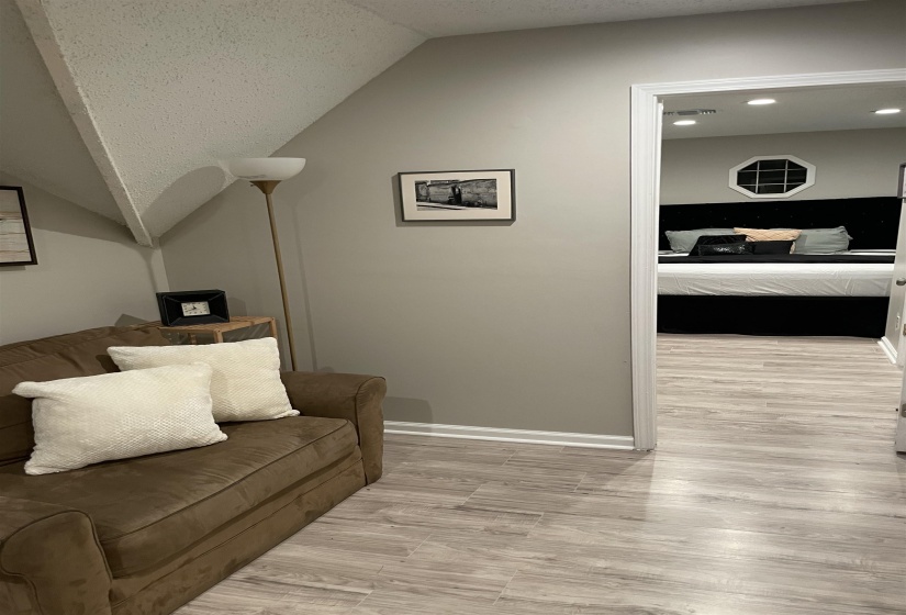 Living area with vaulted ceiling, a textured ceiling, and light wood finished floors