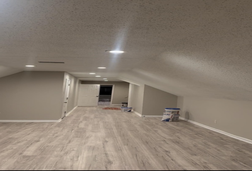 Additional living space featuring a textured ceiling, vaulted ceiling, and light wood finished floors