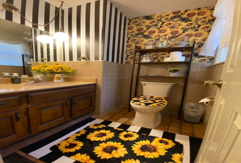 Bathroom featuring wallpapered walls, vanity, a wainscoted wall, tile walls, and dark tile patterned flooring