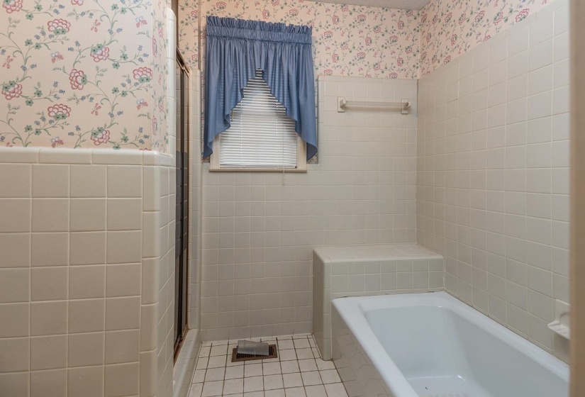 Full bathroom with tile walls, wainscoting, a stall shower, a bath, and light tile patterned floors