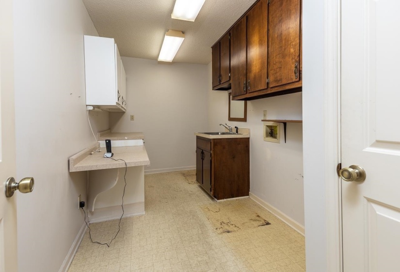 Laundry area with light floors, cabinet space, hookup for a washing machine, and a textured ceiling