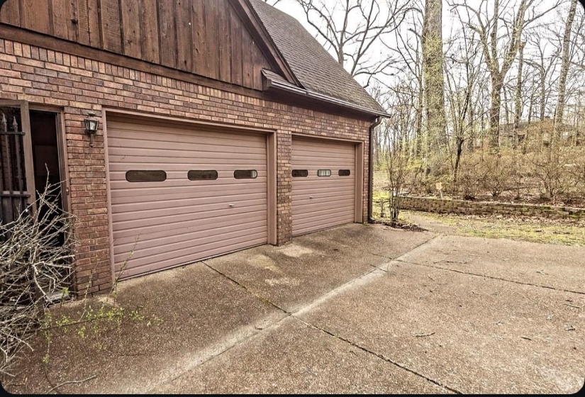 Two-car garage featuring panel doors with horizontal windows, brick exterior, and a concrete driveway