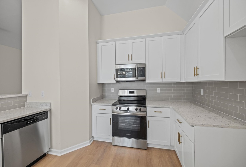 Kitchen featuring appliances with stainless steel finishes, decorative backsplash, white cabinetry, and light wood finished floors
