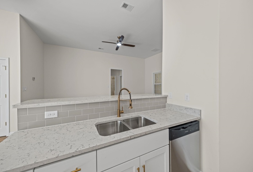 Kitchen featuring light stone counters, stainless steel dishwasher, white cabinets, a peninsula, and ceiling fan