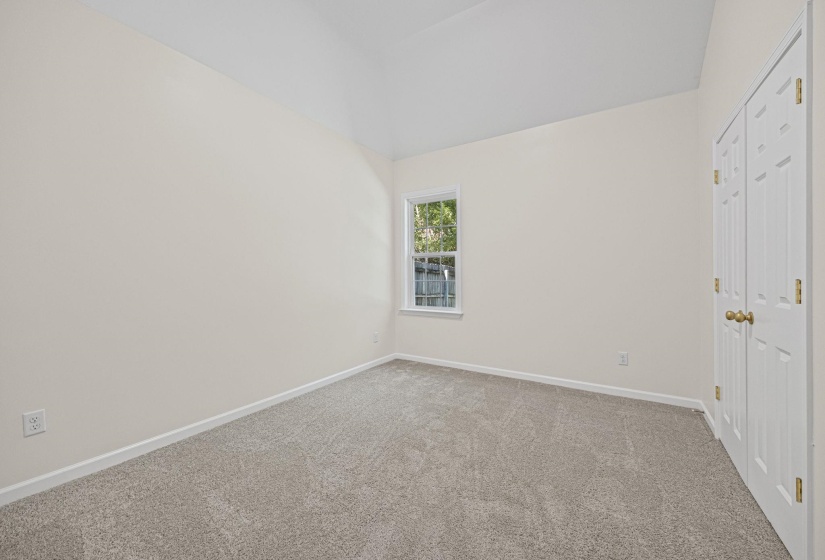 Unfurnished bedroom with carpet, a closet, and vaulted ceiling