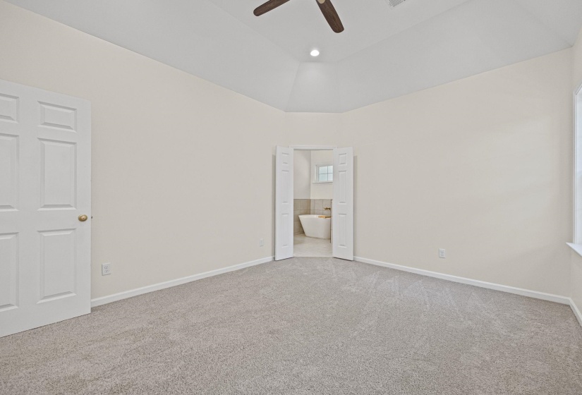 Unfurnished bedroom with light colored carpet, connected bathroom, ceiling fan, high vaulted ceiling, and recessed lighting