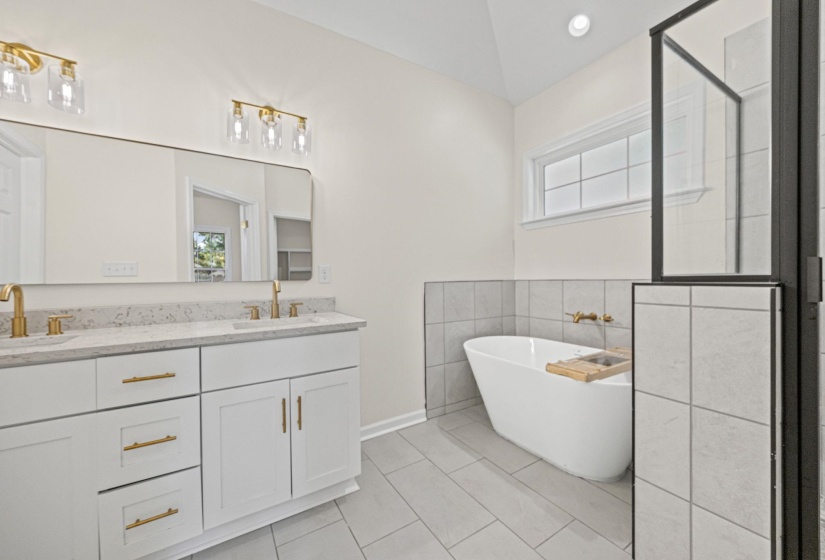 Bathroom with a freestanding bath, double vanity, light tile patterned floors, a shower stall, and tile walls