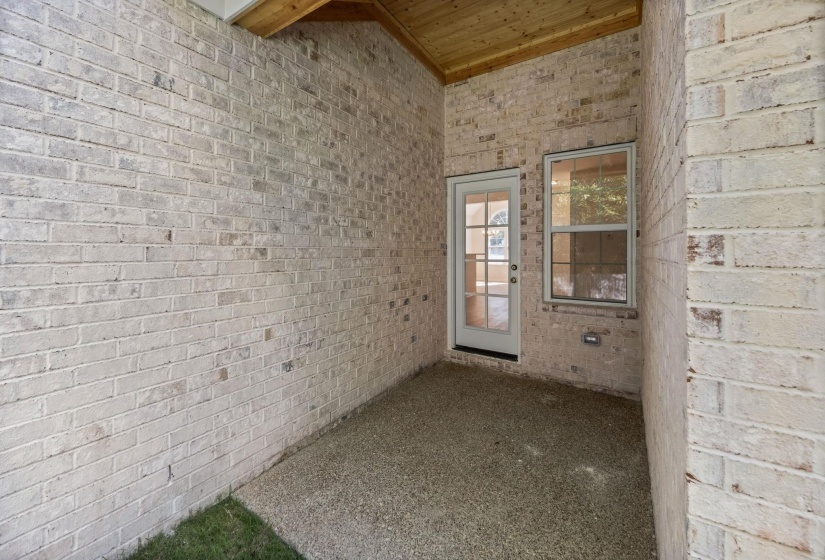 Entrance to property featuring brick siding and a patio area