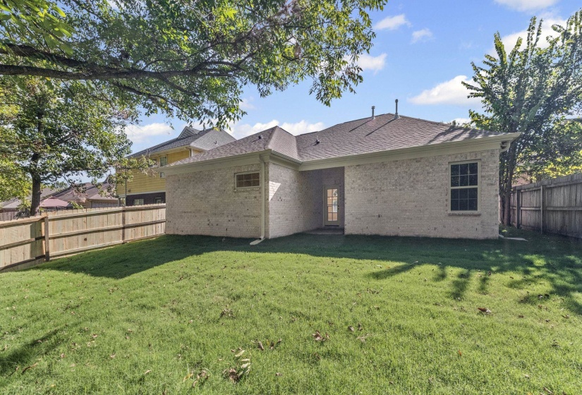 Back of property featuring a fenced backyard, brick siding, and a shingled roof