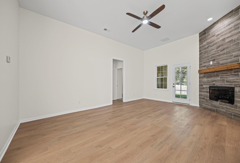 Unfurnished living room featuring a large fireplace, light wood-type flooring, ceiling fan, and recessed lighting