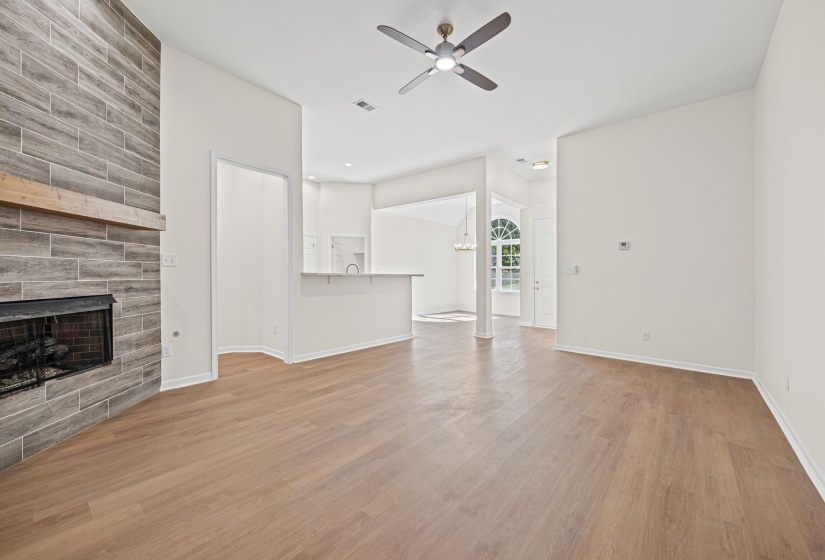 Unfurnished living room featuring light wood-style floors, a fireplace, ceiling fan, and a chandelier