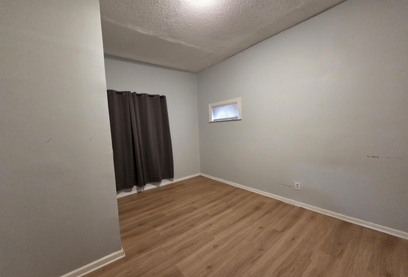 Unfurnished room with a textured ceiling and wood finished floors