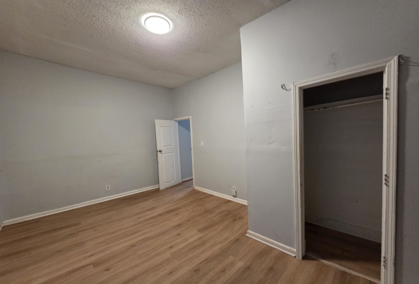 Unfurnished bedroom with a textured ceiling and light wood-type flooring