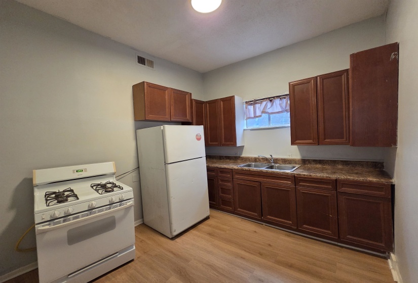 Kitchen featuring white appliances, dark countertops, and light wood-type flooring