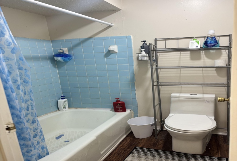 Full bath featuring wood finished floors, toilet, and shower / tub combo