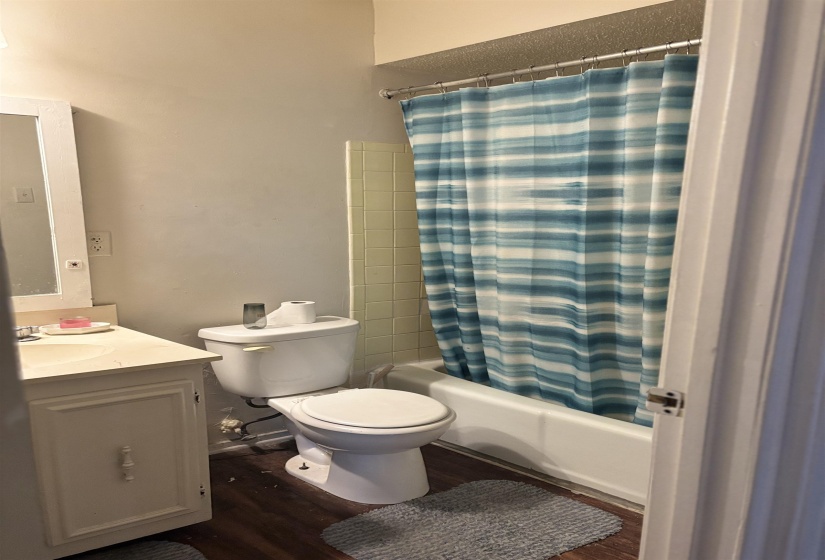 Full bath featuring toilet, wood finished floors, shower / tub combo with curtain, and vanity
