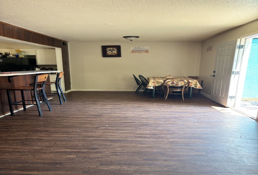 Dining space with a textured ceiling, dark wood-style flooring, and baseboards