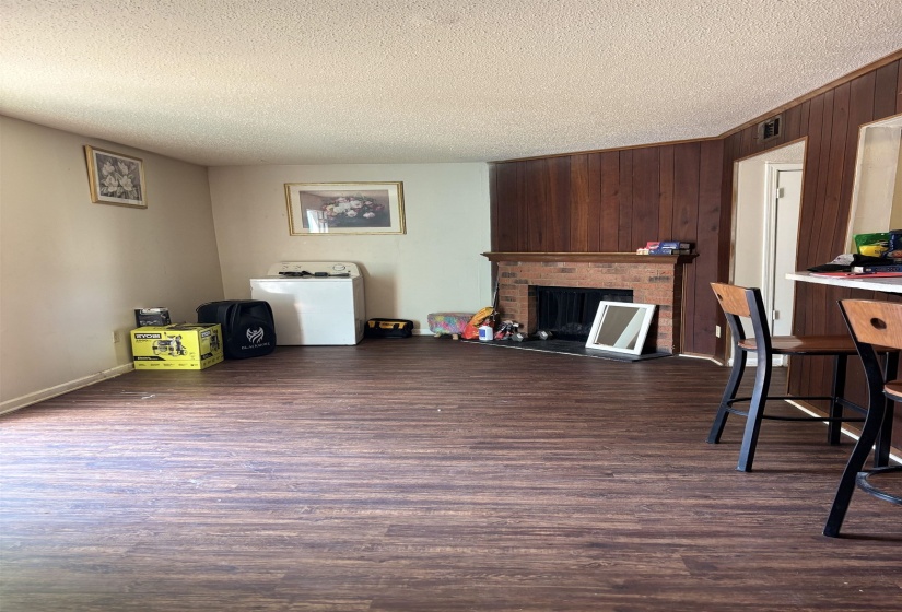 Living area featuring washer / dryer, a textured ceiling, dark wood finished floors, a fireplace, and wood walls