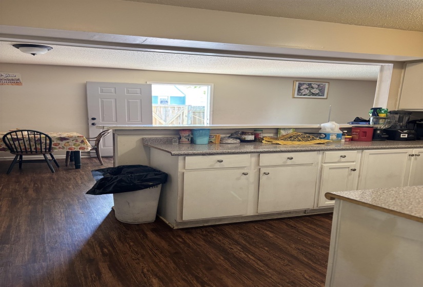 Kitchen with dark wood-style floors, white cabinetry, a peninsula, light countertops, and a textured ceiling