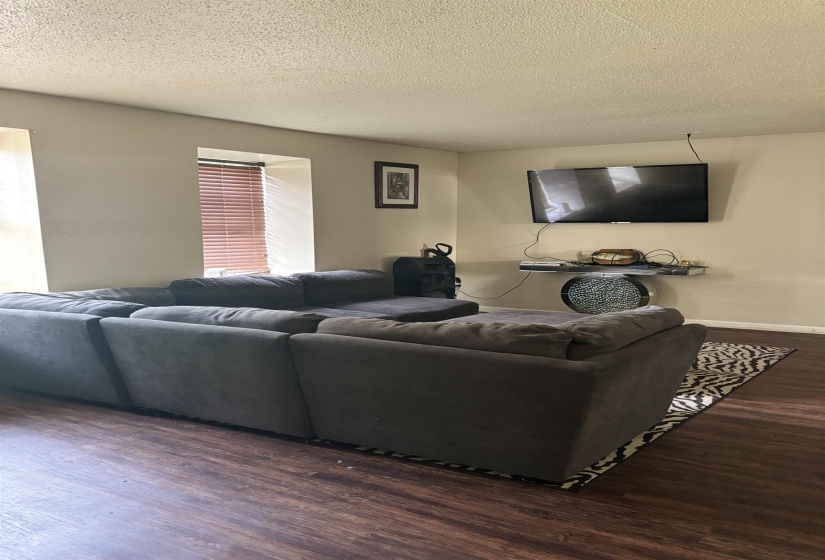 Living area featuring wood finished floors, a textured ceiling, and baseboards
