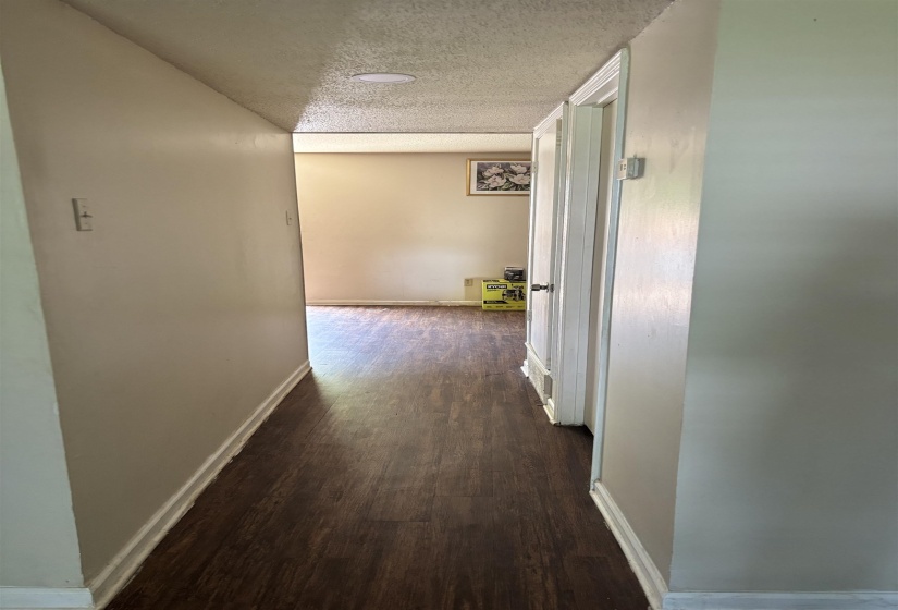 Hall with a textured ceiling, dark wood-style floors, and baseboards