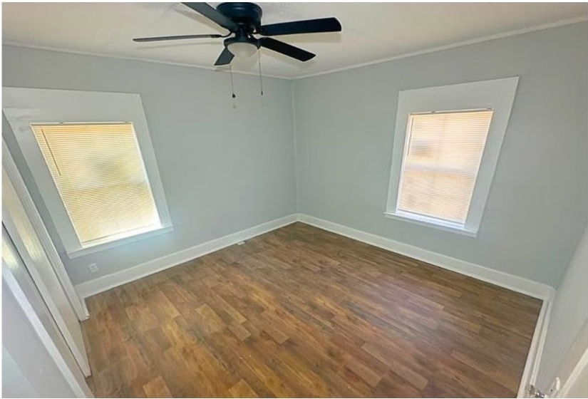 Unfurnished room with dark wood-style flooring, crown molding, and ceiling fan