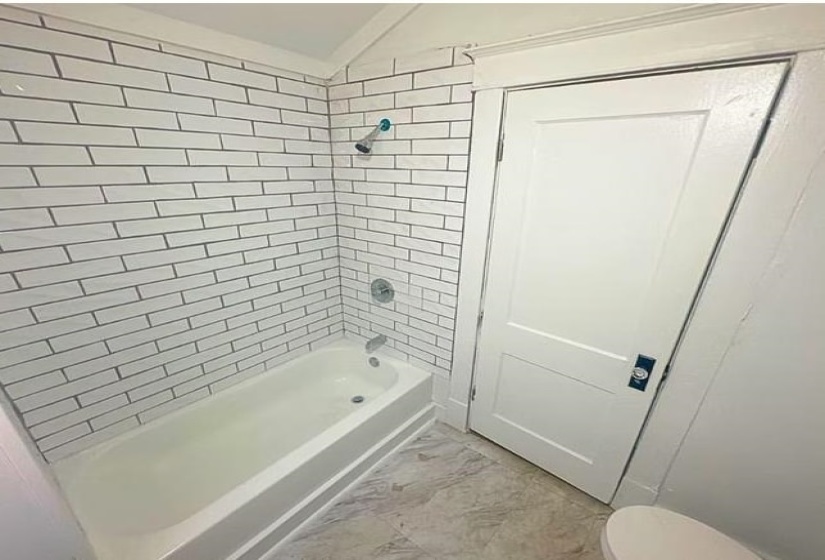 Bathroom with washtub / shower combination and lofted ceiling