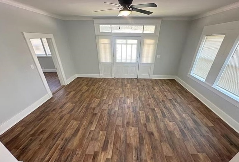 Unfurnished dining area featuring dark wood-style floors, ceiling fan, and crown molding
