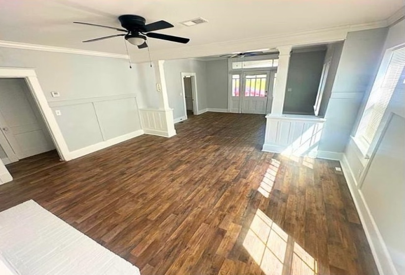 Hall featuring dark wood finished floors, ornamental molding, a decorative wall, and wainscoting