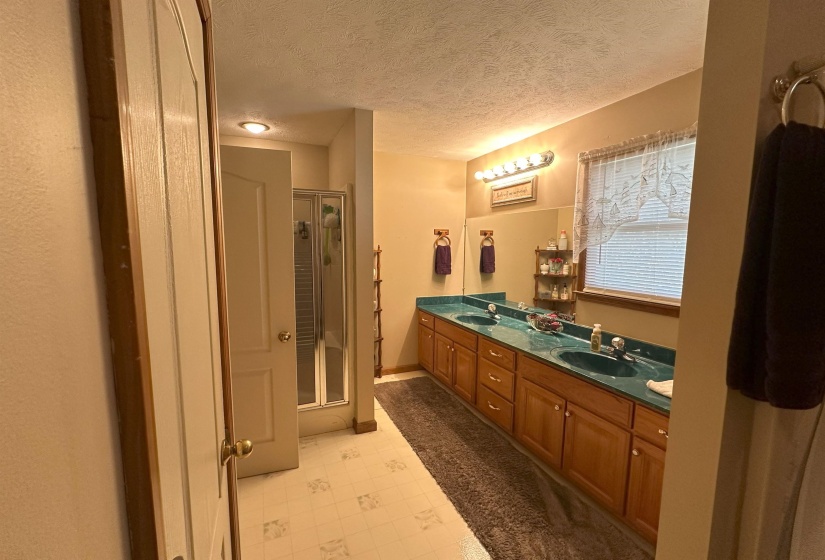Bathroom featuring vanity, walk in shower, and a textured ceiling