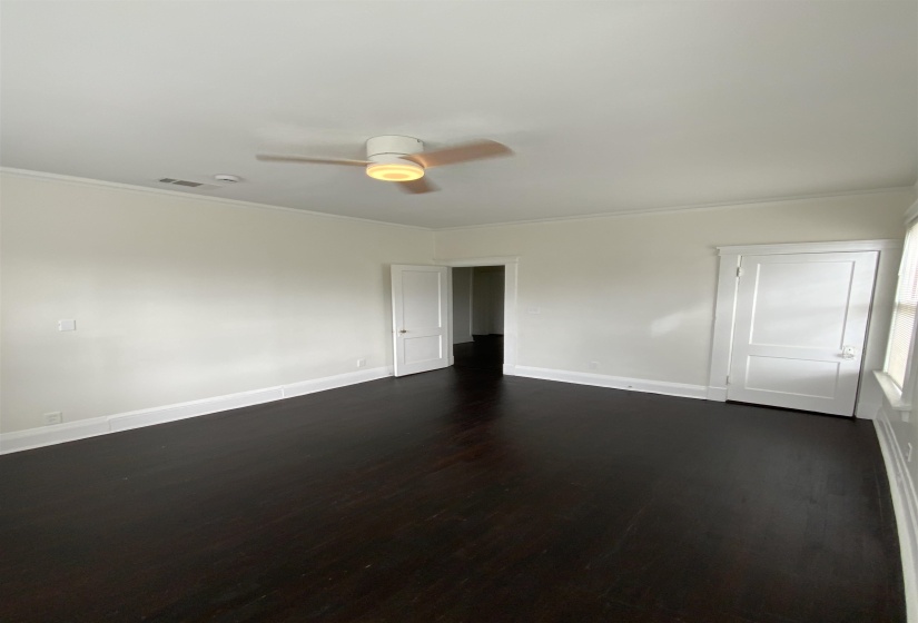 Spare room with dark wood-style floors, a ceiling fan, and ornamental molding