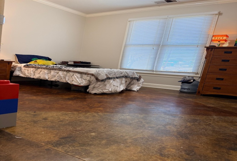 Bedroom featuring ornamental molding and finished concrete flooring