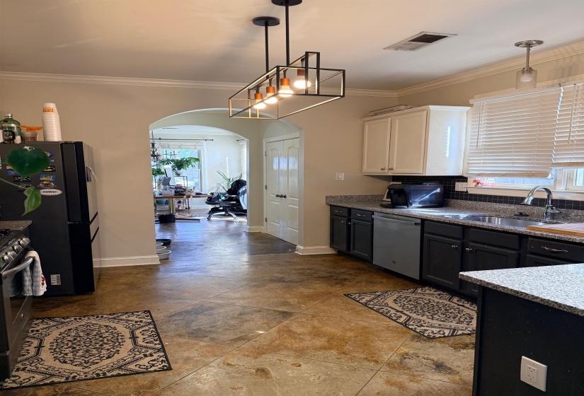 Dual tone kitchen with two tone cabinetry, arched walkways, crown molding, stainless steel appliances, and healthy amount of natural light