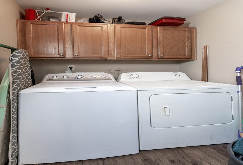 Washroom featuring independent washer and dryer, wood finished floors, and cabinet space