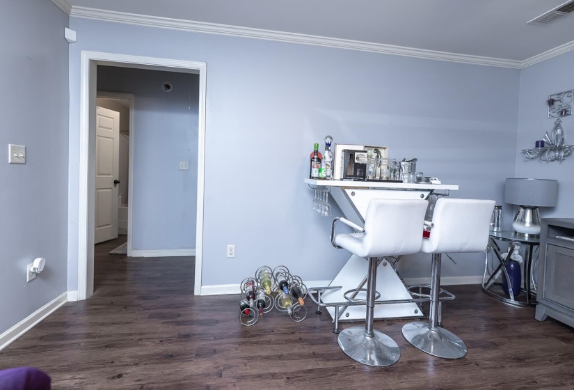 Bar area with crown molding and dark wood-style floors