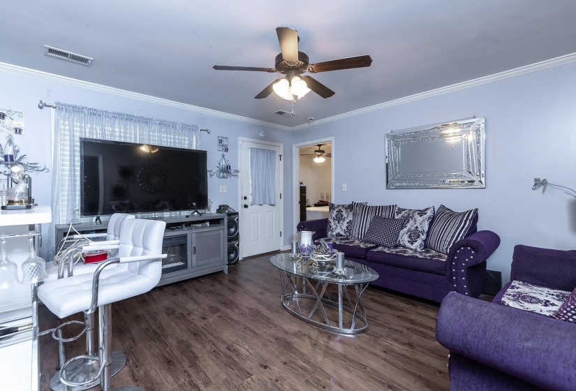 Living room with crown molding, wood finished floors, and ceiling fan
