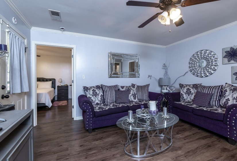 Living area with crown molding, dark wood-type flooring, and ceiling fan