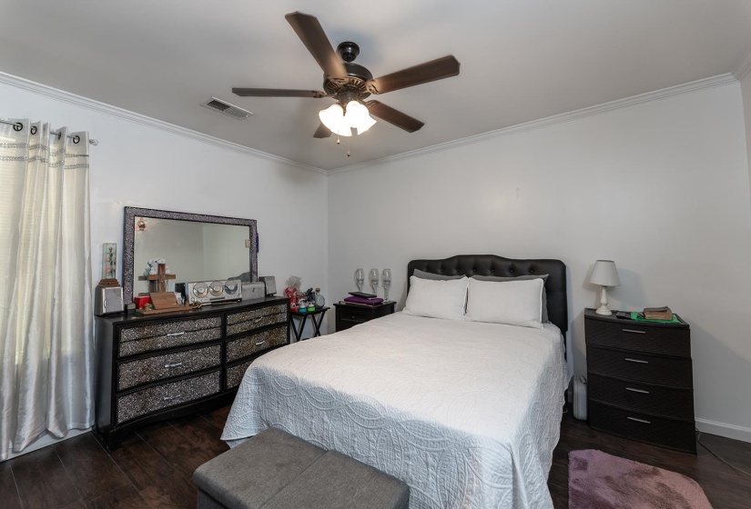 Bedroom featuring ornamental molding, dark wood finished floors, and ceiling fan